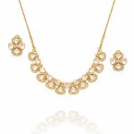 Gold-plated statement necklace set with matching stud earrings, featuring pear-shaped and oval crystal stones arranged in a cascading design, photographed on a white background with the necklace appearing to hang in the air and a soft reflection below