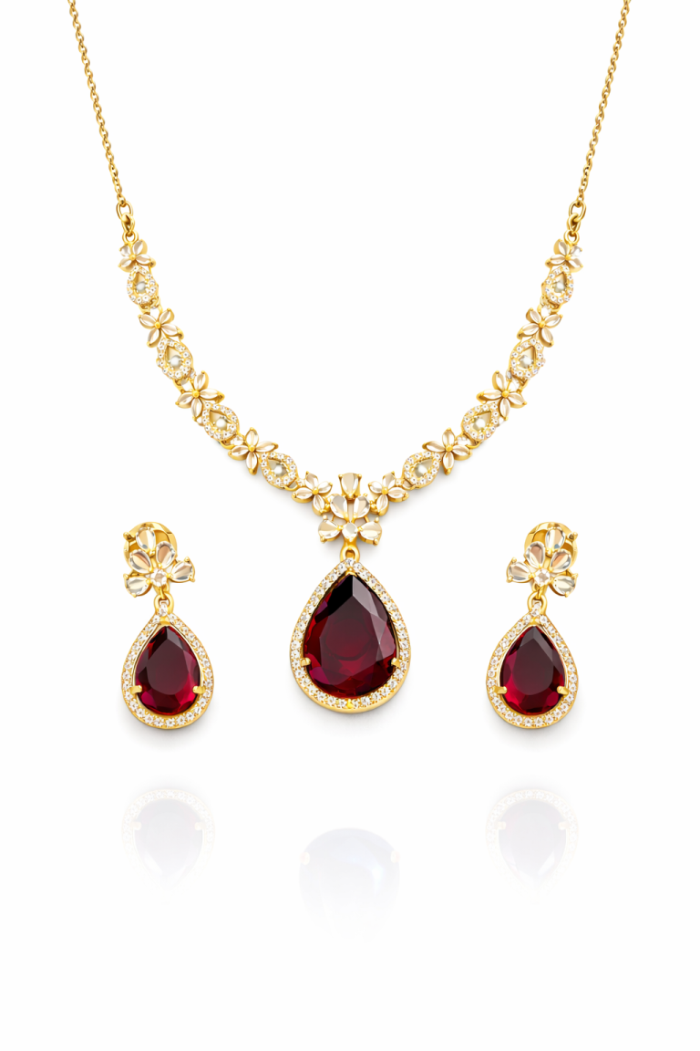 Gold plated ruby teardrop necklace set with cubic zirconia stones and matching earrings placed on marble background