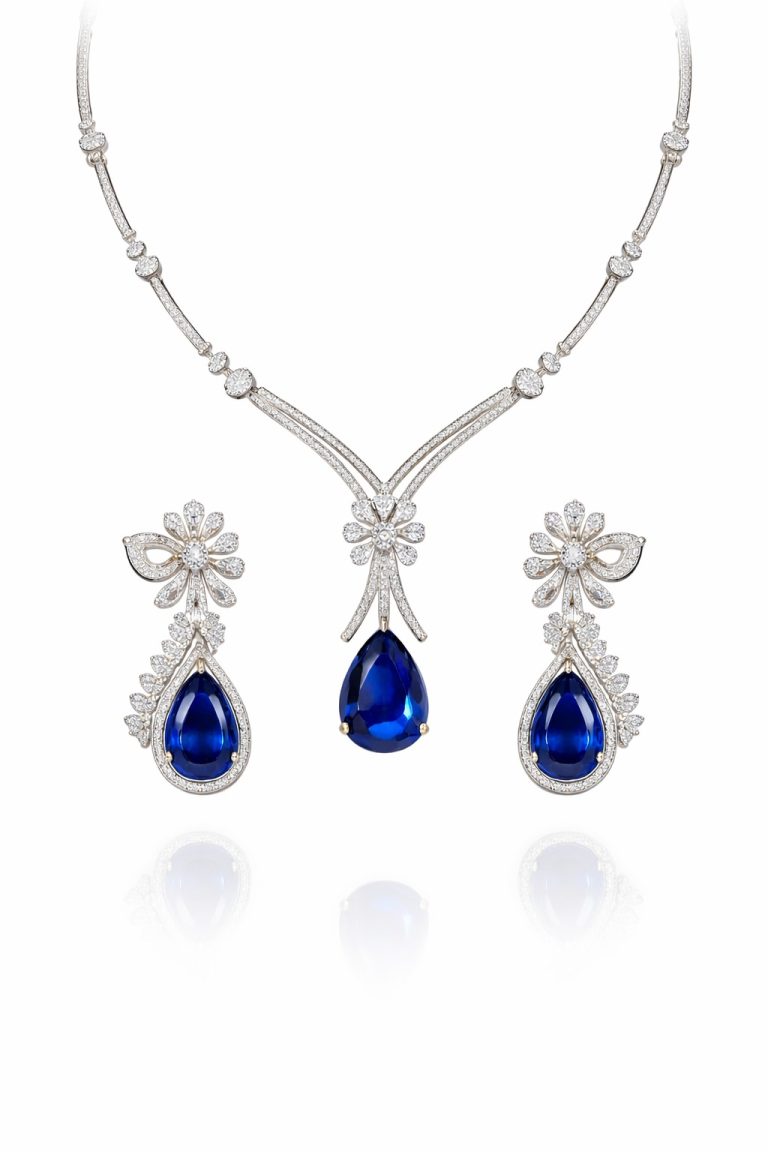 Nyveera sapphire blue teardrop CZ necklace set with matching floral drop earrings, elegant gold plated cubic zirconia jewelry for weddings and party wear.
